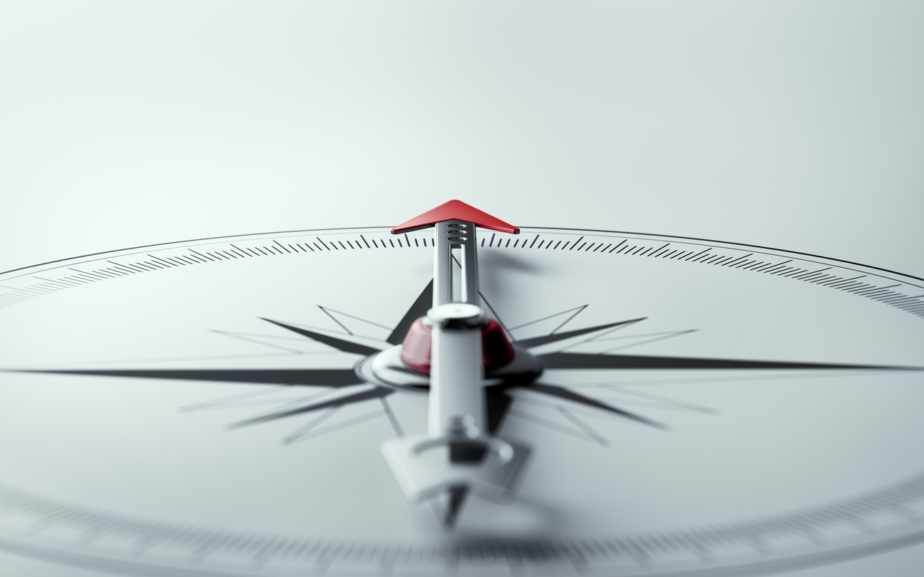 Compass on white background with selective focus. Compass is lit from the upper left corner of composition. Horizontal composition with copy space.