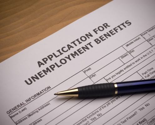 application for unemployment benefits on a desk with a pen on top