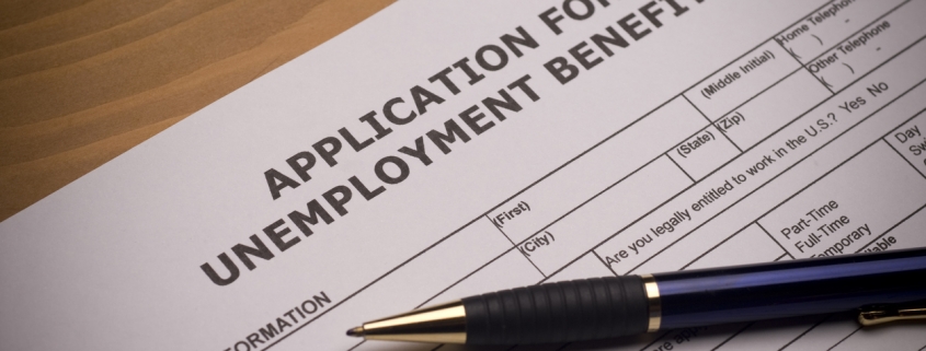 application for unemployment benefits on a desk with a pen on top