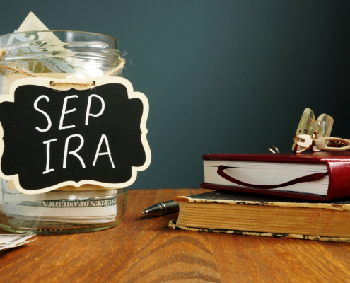 SEP IRA written on a jar of money on a table with books and glasses