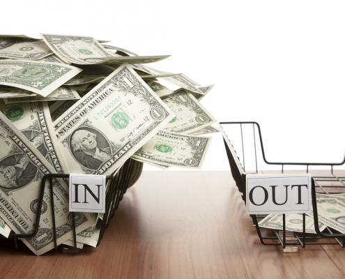 two baskets of dollar bills that say in and out