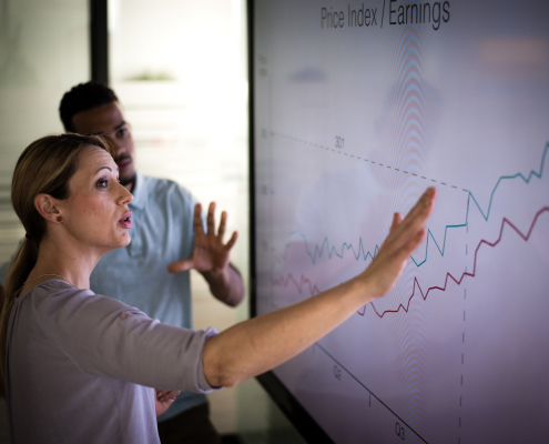 businessman and businesswoman looking at a graph on a screen