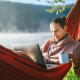self-employed worker in a hammock with computer and coffee