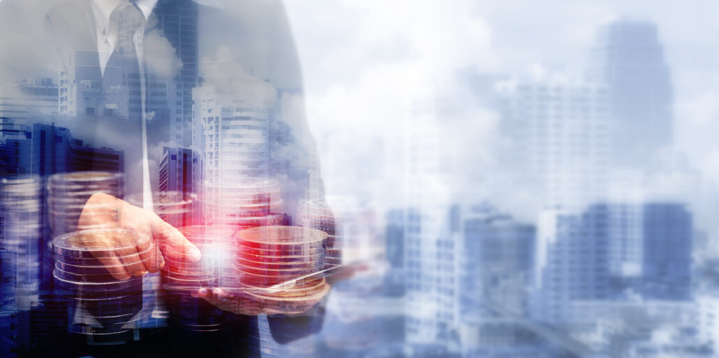Business professional holding stacked coins over a city backdrop, symbolizing January tax planning and financial flexibility