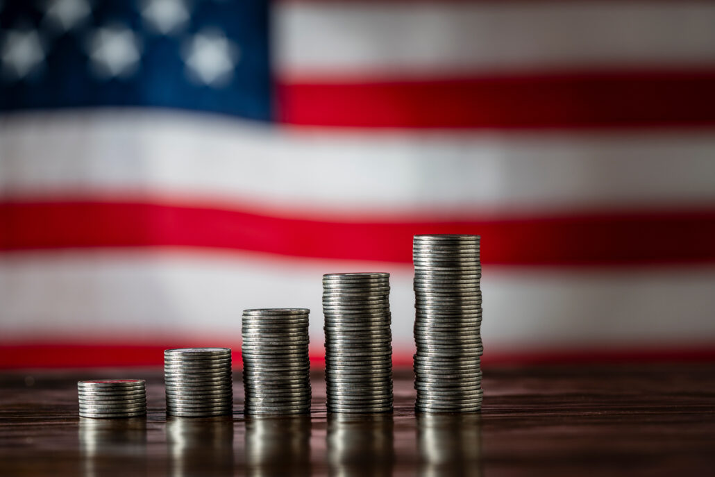 Stacks of coins in front of a U.S. flag, representing retirement tax planning choices for high earners