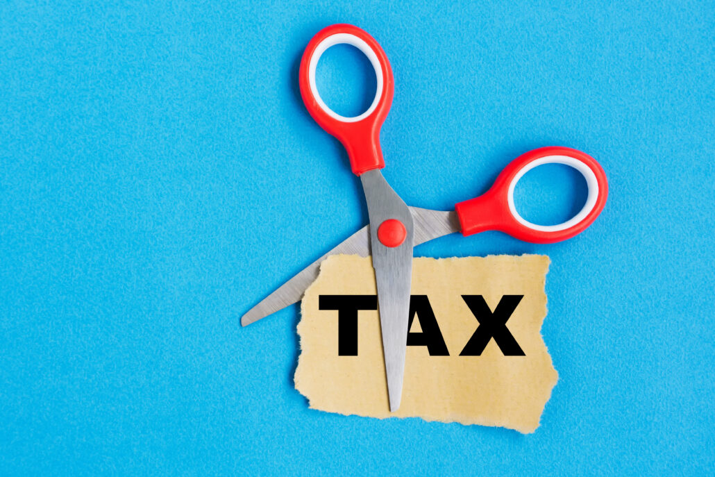 Red scissors cutting the word TAX on a torn paper label, representing tax planning vs tax preparation fees and what is deductible