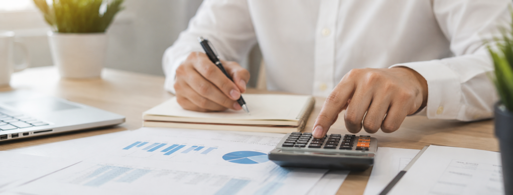 Business owner reviewing tax documents and calculating estimated safe harbor tax payments at office desk